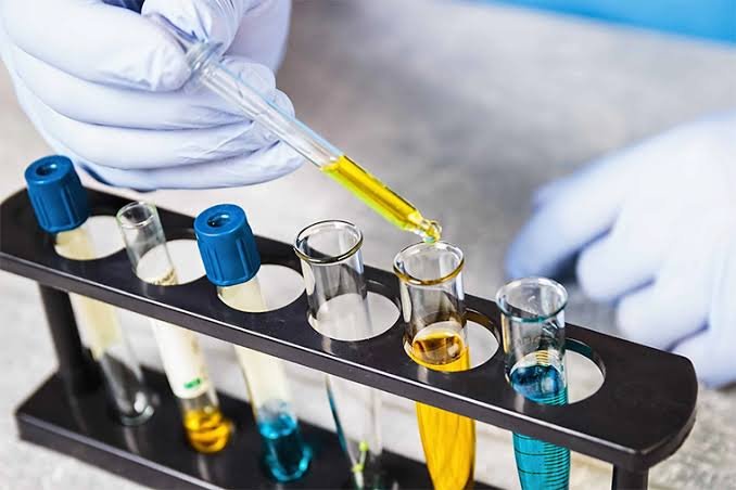 Laboratory technician pouring a reagent between glass beakers